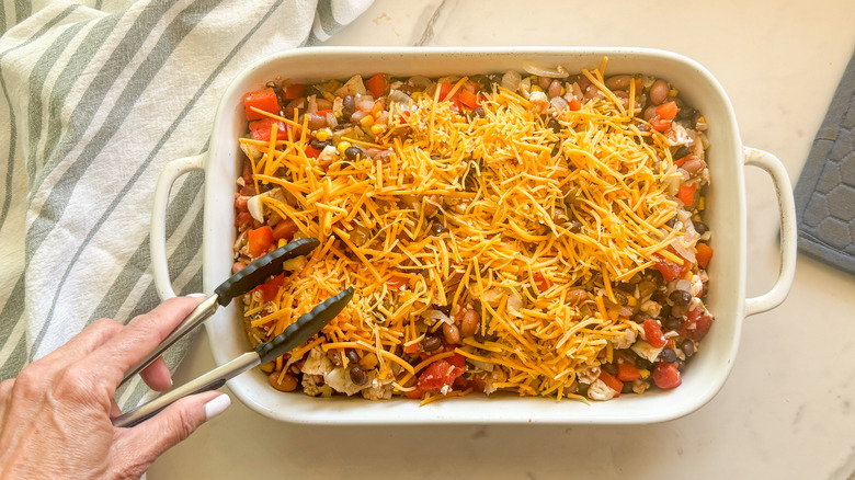 tongs adding cheese to dish