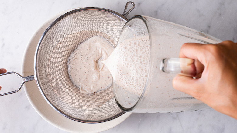 straining horchata into a bowl