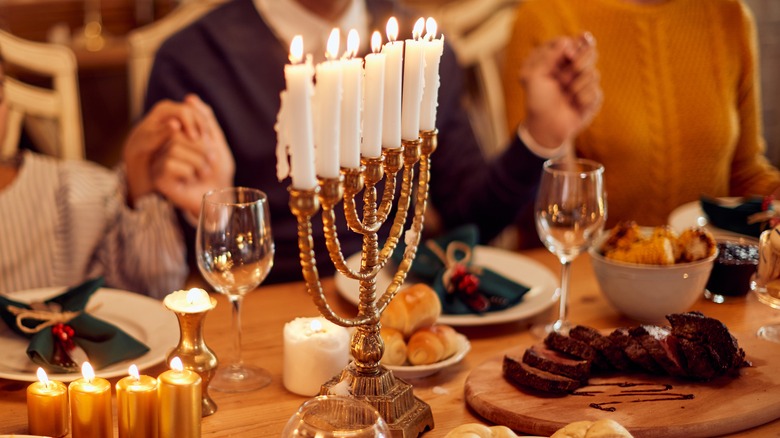 A lit menorah at Hanukkah dinner table
