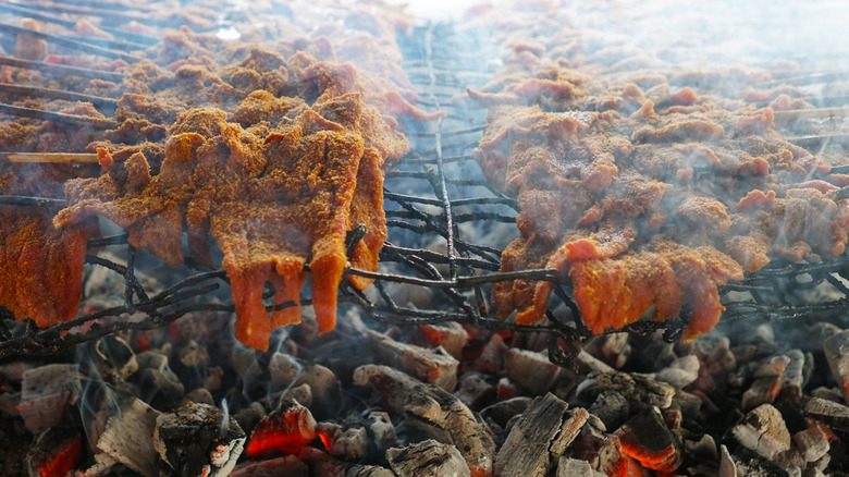 Nigerian suya roasting over hot coals.