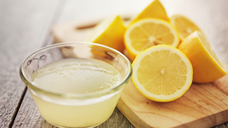 Lemon juice with lemons on cutting board