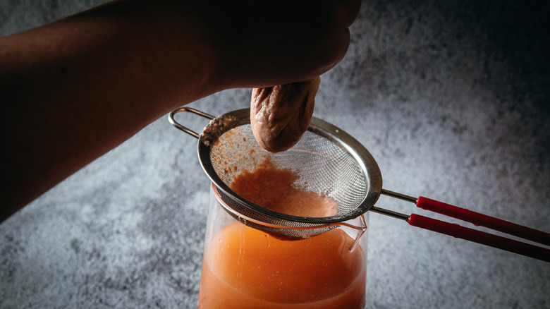 Squeezing cheesecloth over strainer