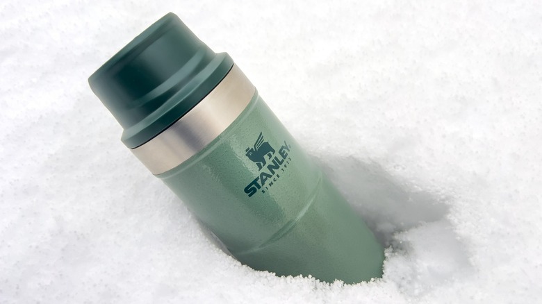 A green Stanley thermos in the snow