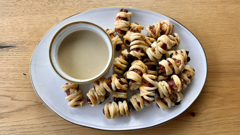 Mini sausage mummies on serving tray with dipping sauce