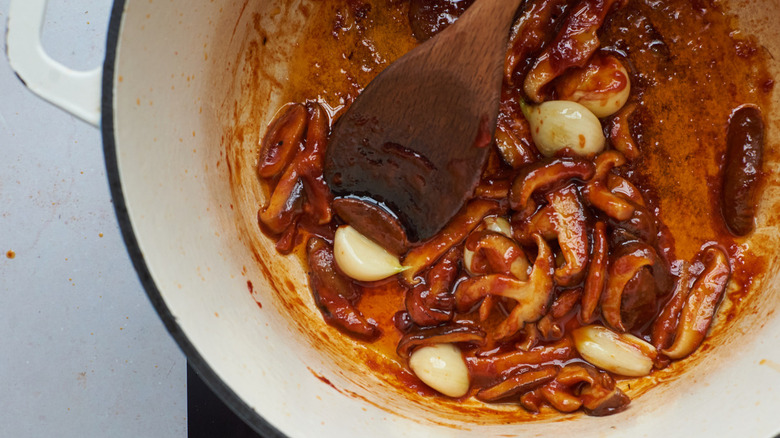 stirring mushrooms and gochujang in pot