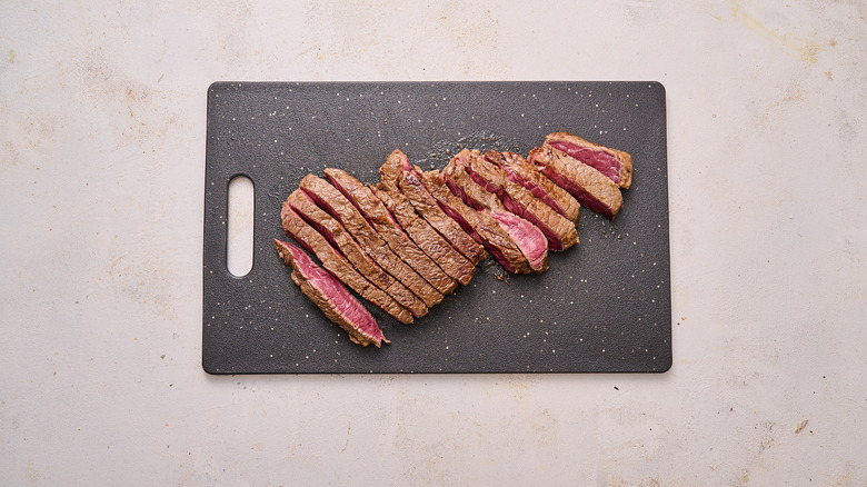 slicing steak on cutting board