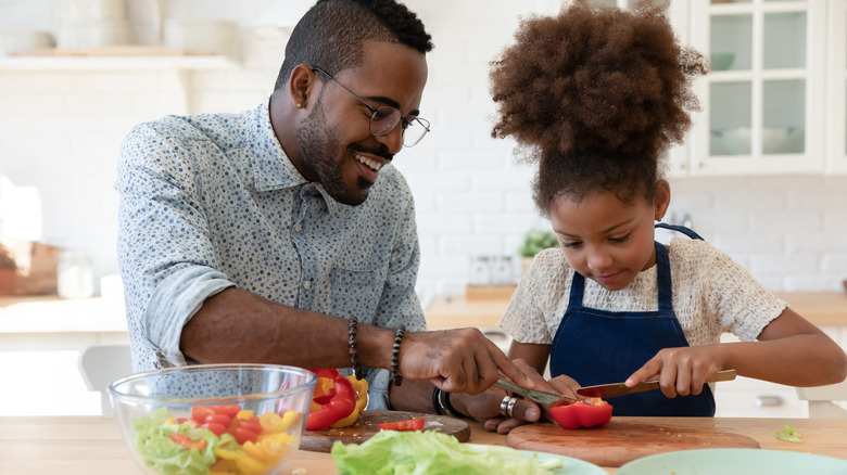 father and daughter cutting vegetables