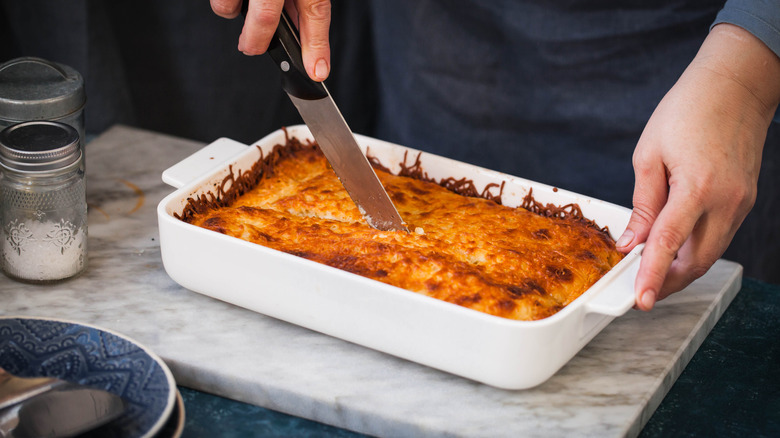 Knife cutting lasagna in dish