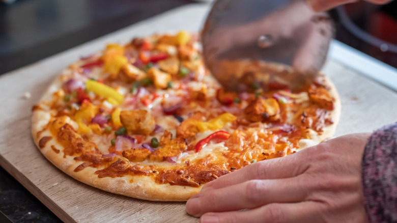 Pizza cutter cutting pizza