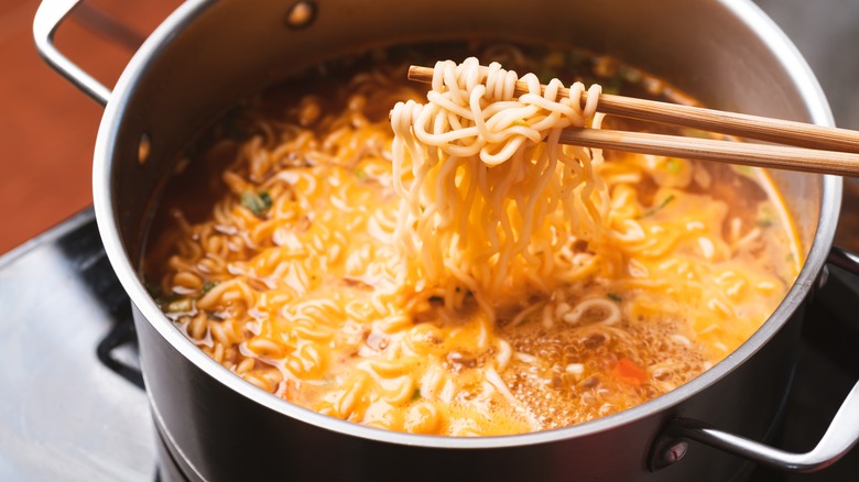 chopsticks lifting ramen noodles out of a pot