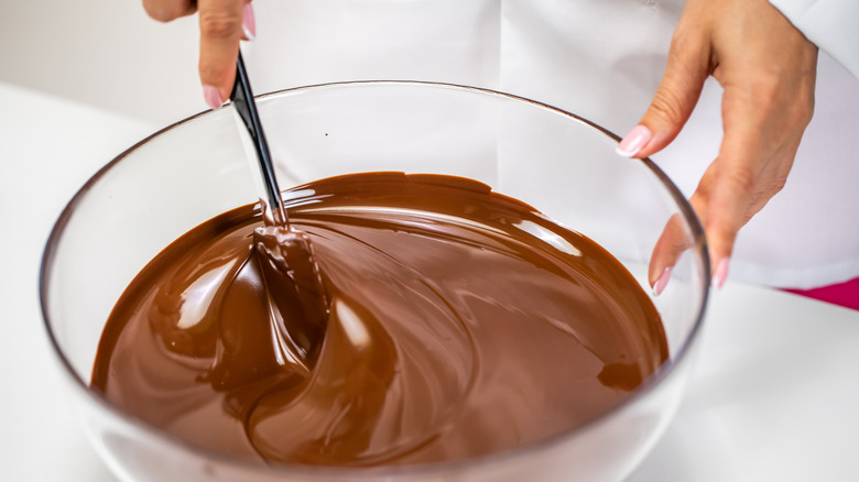 woman mixing melted chocolate in a clear bowl