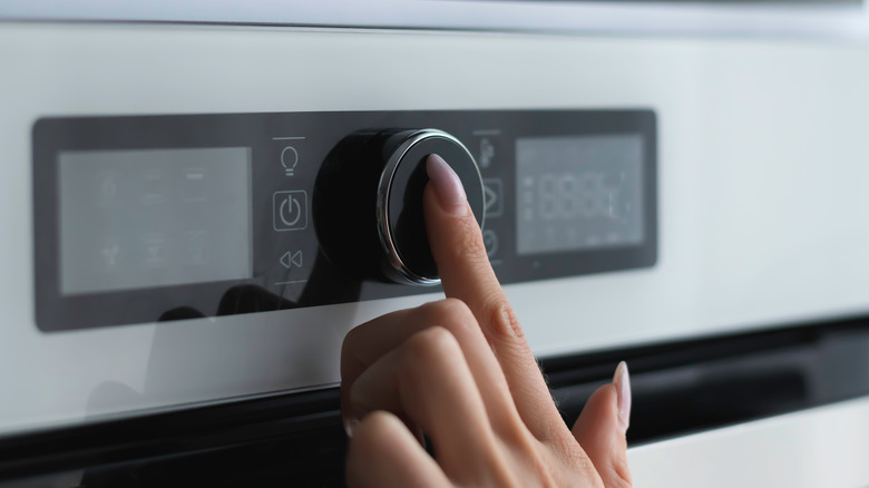 a finger pressing an oven button