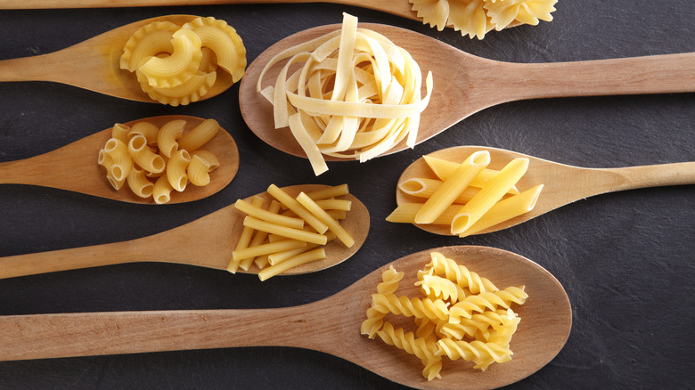 dried pasta shapes on wooden spoons