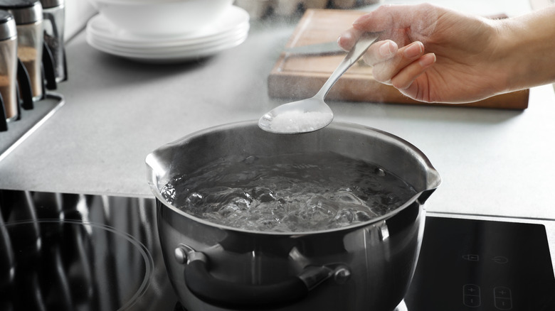 woman adding salt to pasta water