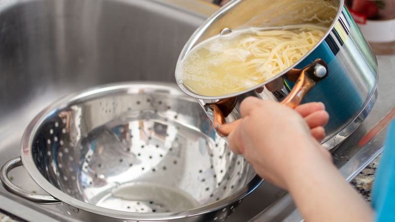 woman draining spaghetti into colander