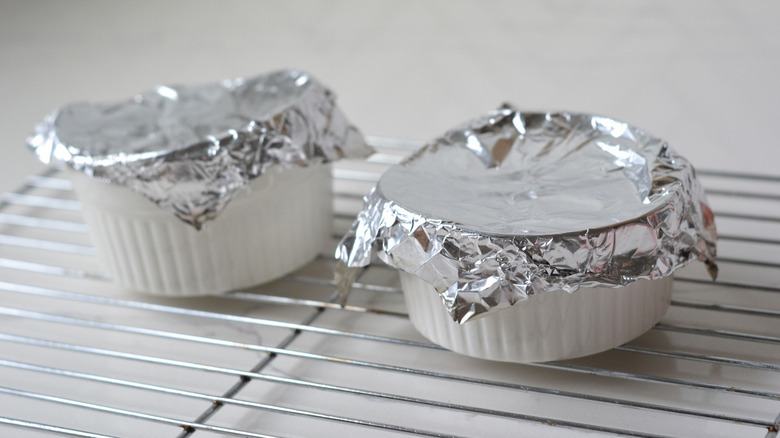 foil-covered ramekins of creme brulee on wire rack