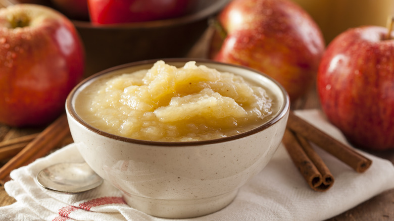 A bow of applesauce, apples, and cinnamon sticks