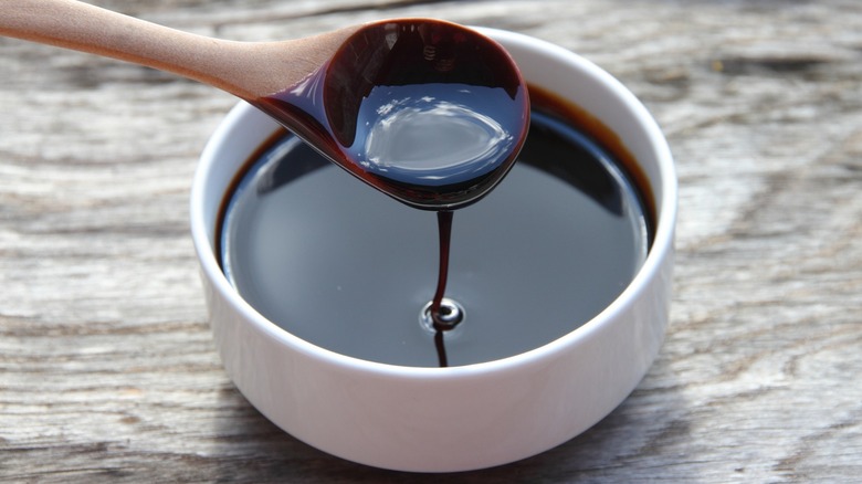 A wooden spoon in a small white bowl of molasses