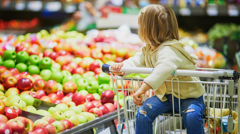 Little girl staring at apples at the store