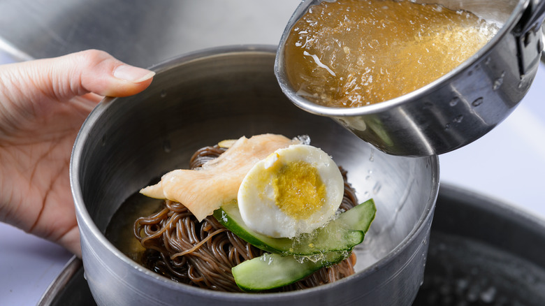 icy broth being poured in naengmyeon
