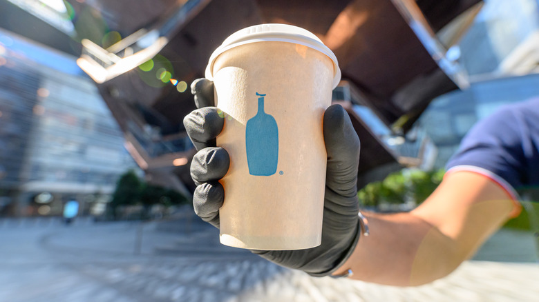 person holding Blue Bottle coffee cup