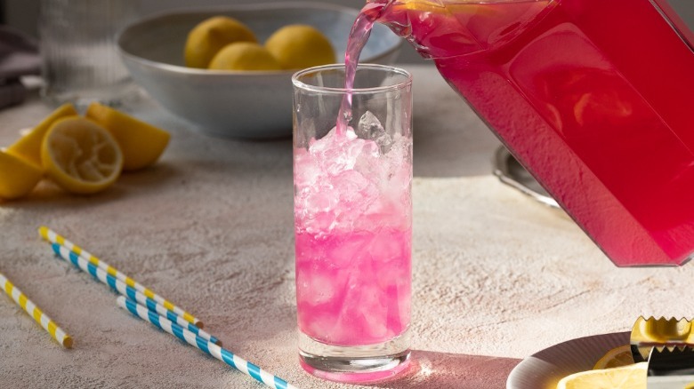 pouring pink lemonade into glass