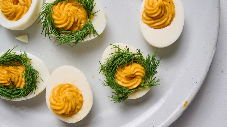 deviled eggs with dill wreaths on white plate