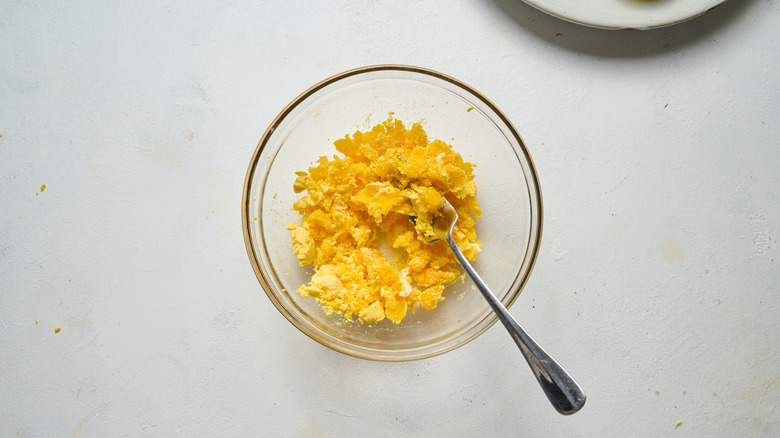 smushed egg yolks in bowl with fork