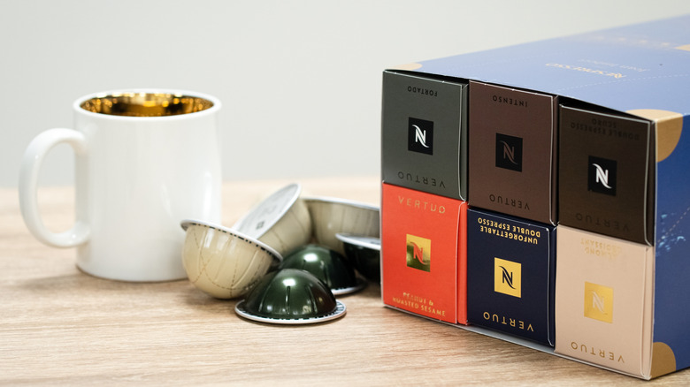 Nespresso pods, both in and out of their containers next to a coffee mug