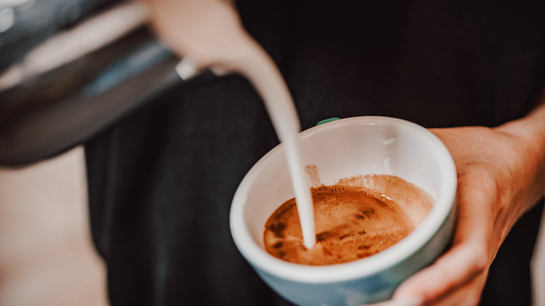 Pouring froth onto coffee