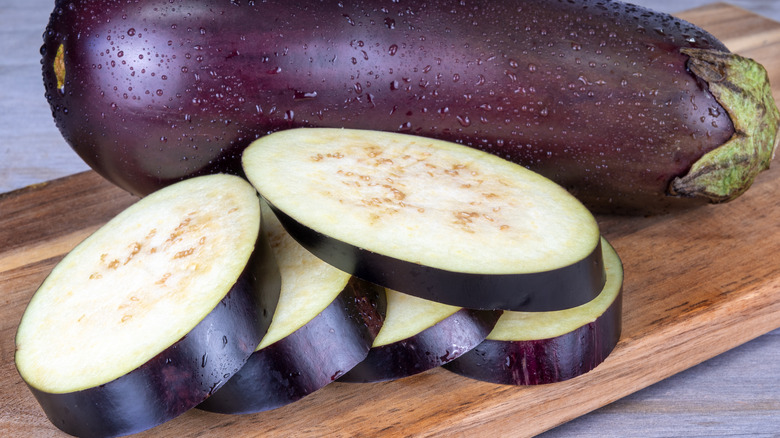 Whole and sliced eggplant on cutting board