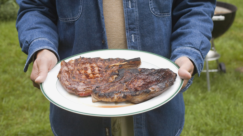 Man holding steak on plate 