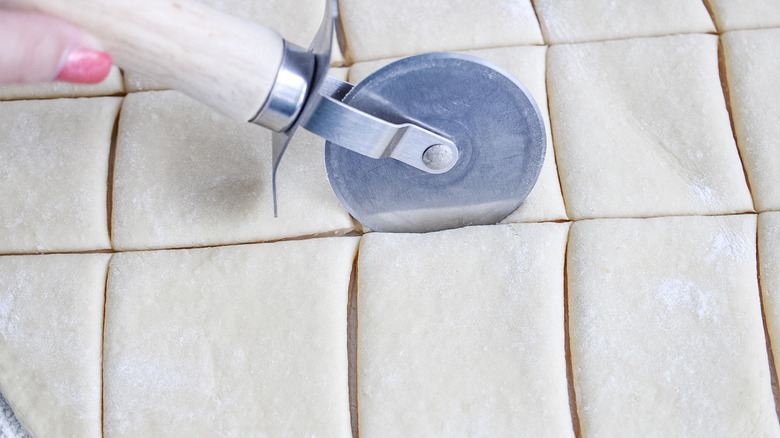 pizza cutter cutting through dough