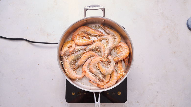 cooking garlic in skillet with shrimp