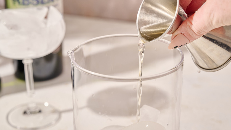 Pouring alcohol into mixing glass