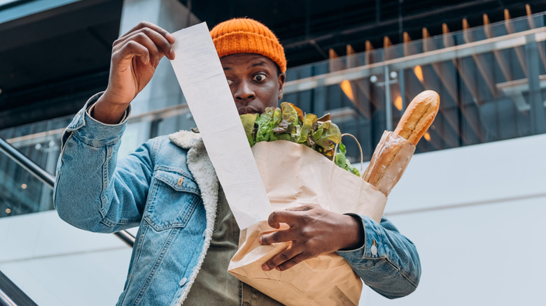 Man looks shocked at grocery receipt