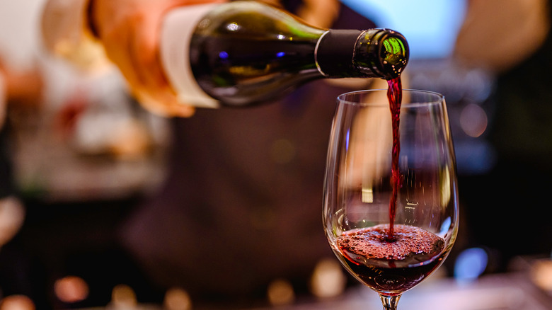 A bartender pouring a glass of red wine