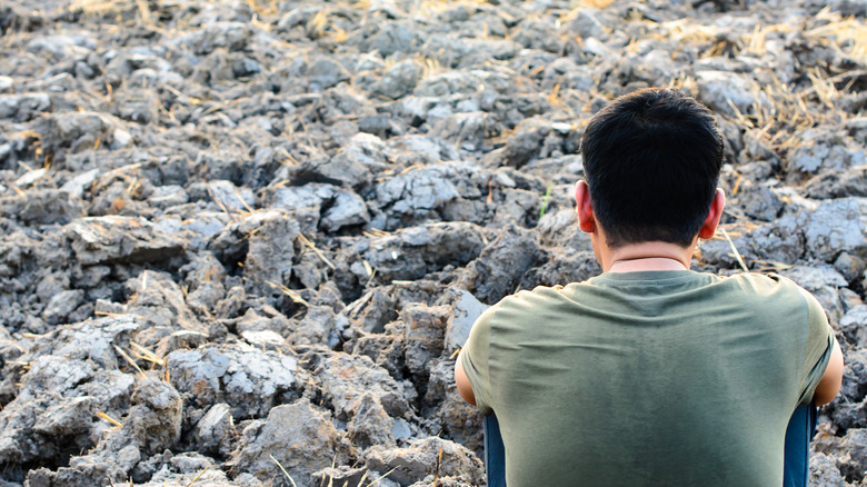 Man looking out over barren field