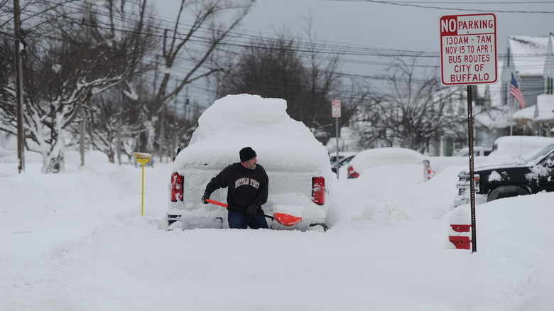 man shoveling snow behind truck