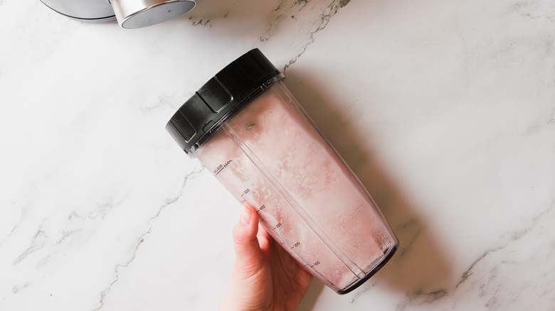 Hand holding blender cup with frozen drink