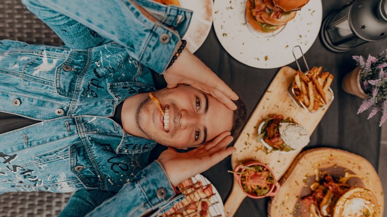 Nico Norena resting on table with plates of food