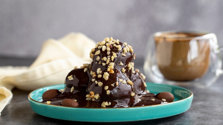 Profiteroles covered in chocolate sauce and peanuts