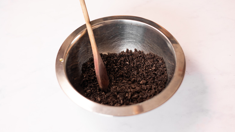 oreo crumbs in metal bowl with wooden spoon