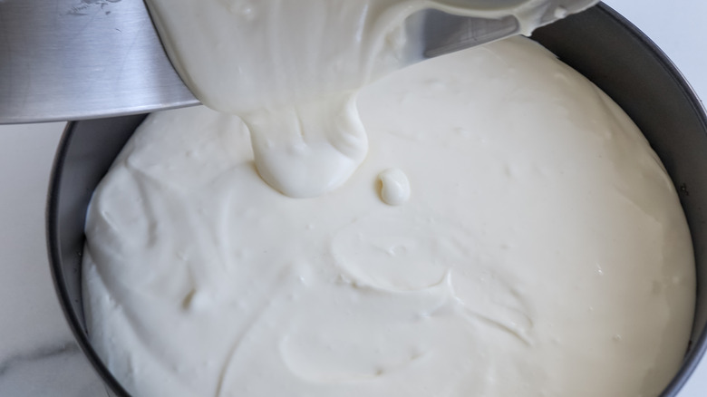 pouring cheesecake filling into crust