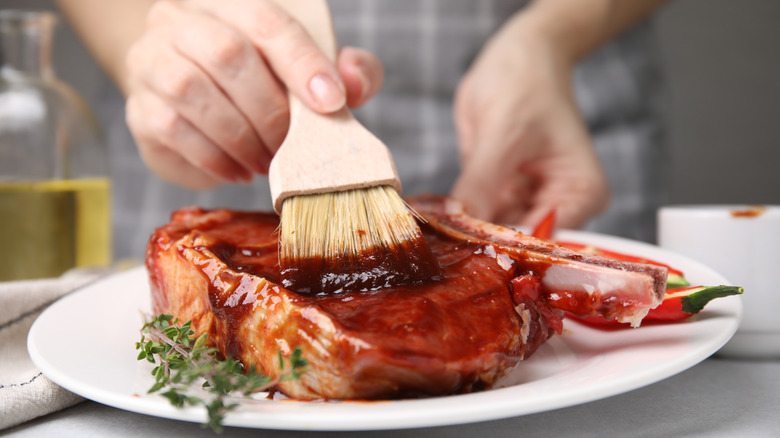 basting marinade onto a raw steak