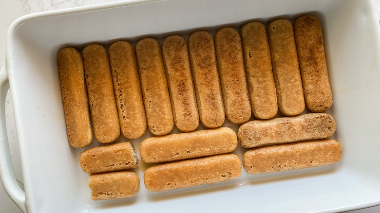 espresso coated ladyfingers at the bottom of the baking pan