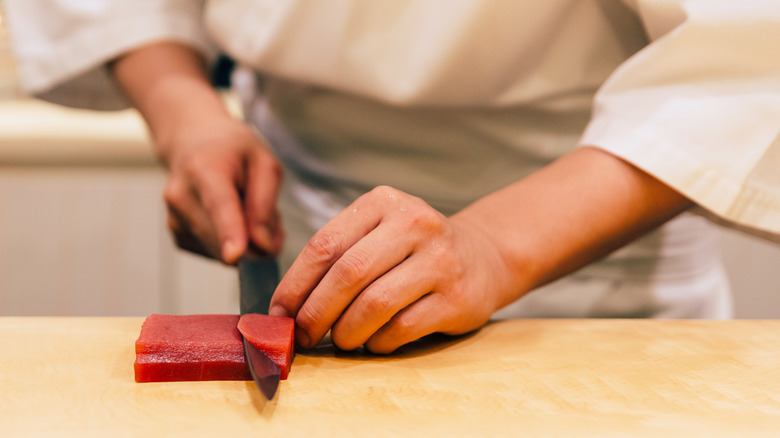 A sushi chef slicing bluefin tuna