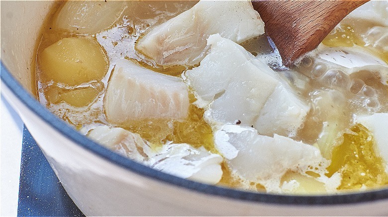 stirring fish in simmering broth