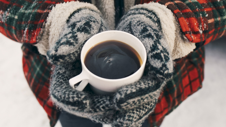 gloved hands holding black coffee