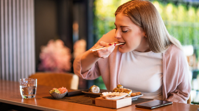 Person eating sushi with chopsticks